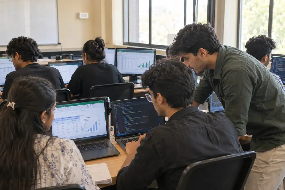 Students practising in the lab with Excel, SQL and dashboards while a mentor helps