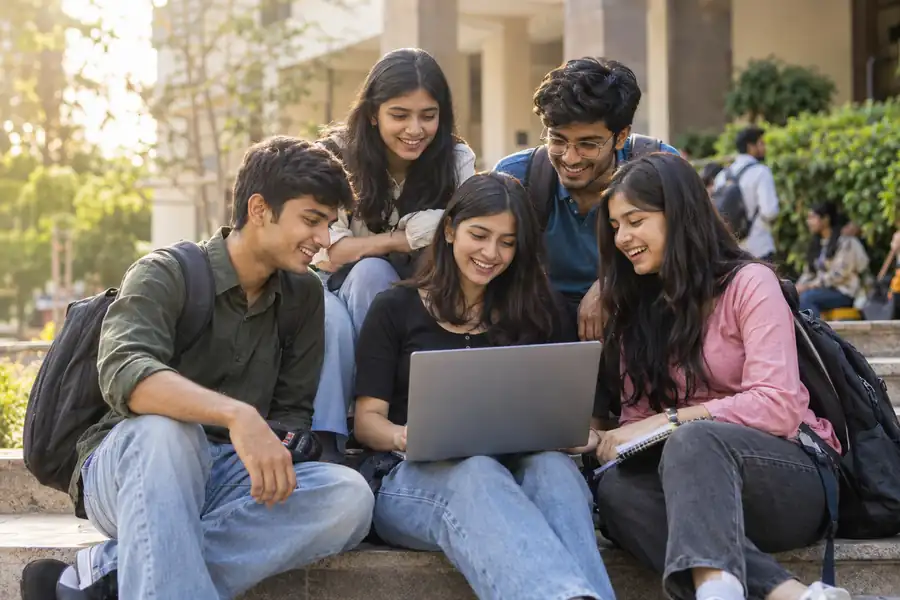 Students and early-career learners studying data analytics together outdoors with a laptop